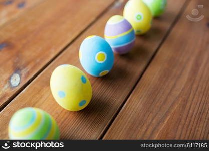 easter, holidays, tradition and object concept - close up of colored easter eggs on wooden surface