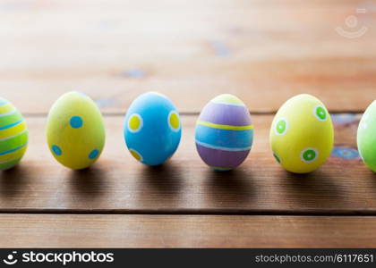 easter, holidays, tradition and object concept - close up of colored easter eggs on wooden surface