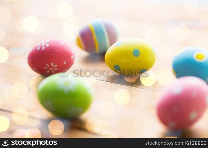 easter, holidays, tradition and object concept - close up of colored easter eggs on wooden surface