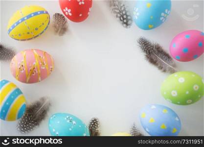 easter, holidays, tradition and object concept - close up of colored eggs and feathers on white background. close up of colored easter eggs and feathers