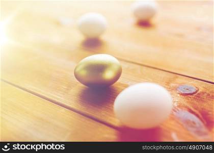 easter, holidays, tradition and object concept - close up of golden and white easter eggs on wood. close up of golden and white easter eggs on wood