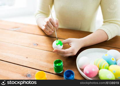 easter, holidays, tradition and people concept - close up of woman hands coloring easter eggs with colors and brush