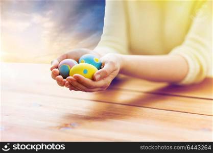 easter, holidays, tradition and people concept - close up of woman hands holding colored eggs over sky background. close up of woman hands with colored easter eggs