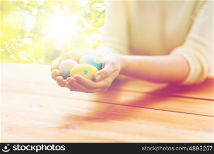 easter, holidays, tradition and people concept - close up of woman hands holding colored easter eggs