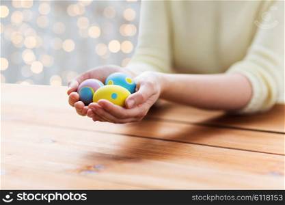 easter, holidays, tradition and people concept - close up of woman hands holding colored easter eggs
