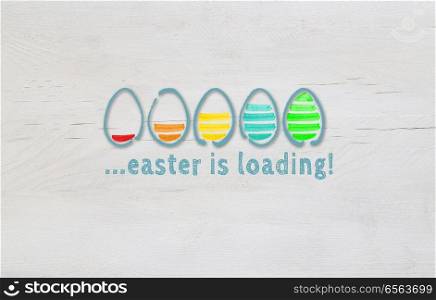 Easter is loading concept with colorful eggs on light wood.. Easter is loading concept with colorful eggs on light wood