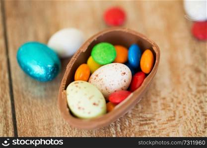easter, junk-food, confectionery and unhealthy eating concept - close up of chocolate egg and candy drops on table. chocolate easter egg and candy drops on table