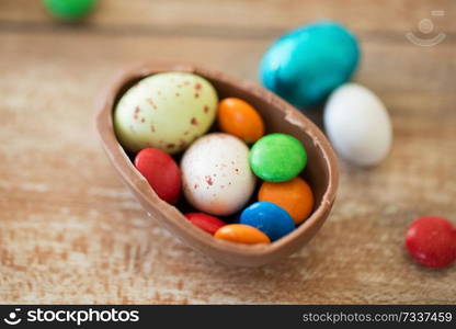 easter, junk-food, confectionery and unhealthy eating concept - close up of chocolate egg and candy drops on table. chocolate easter egg and candy drops on table