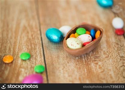 easter, junk-food, confectionery and unhealthy eating concept - close up of chocolate egg and candy drops on table. chocolate easter egg and candy drops on table