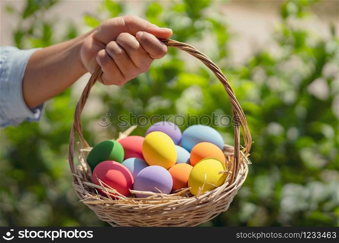 easter painted eggs in basket hand holding on green background