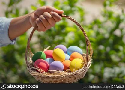 easter painted eggs in basket hand holding on green background