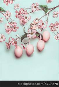 Easter pastel pink layout with hanged eggs and decor blossom on turquoise background