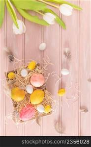 Easter pink, yellow and white eggs in wooden box and white tulips