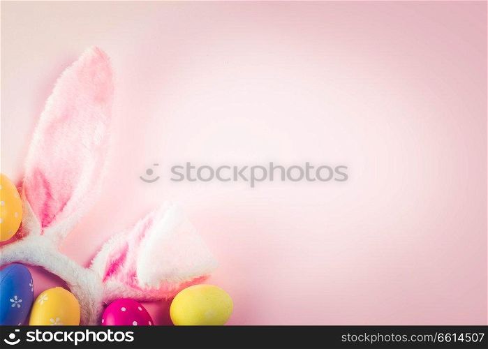 Easter rabbit ears and colored easter colored eggs on pink background with copy space, retro toned. Easter scene with rabbit ears