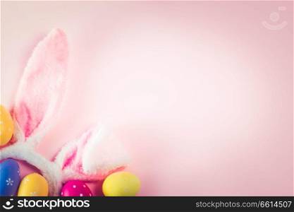 Easter rabbit ears and colored easter colored eggs on pink background with copy space, retro toned. Easter scene with rabbit ears