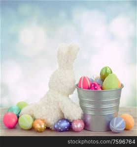 easter rabbit with metal pot full of eggs on blue background. egg hunt with easter bunny