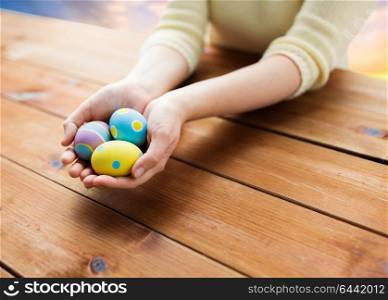 easter, religious holidays and people concept - close up of woman hands holding colored eggs over sky background. close up of woman hands with colored easter eggs