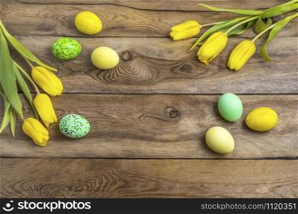 Easter rustic wooden background with yellow and green painted eggs and tulips. Happy Easter greeting card, copy space.