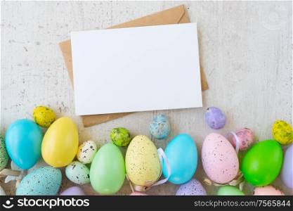 Easter scene with colored eggs border, flat lay on white wooden background, copy space on empty card. Easter colored eggs