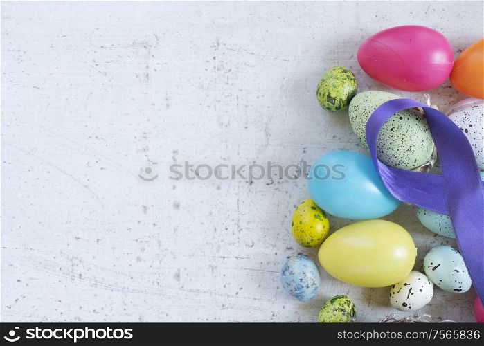 Easter scene with colored eggs border, flat lay on white wooden background with copy space. Easter colored eggs