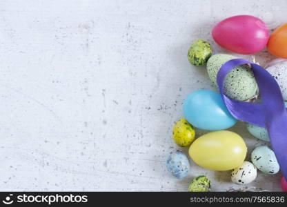 Easter scene with colored eggs border, flat lay on white wooden background with copy space. Easter colored eggs