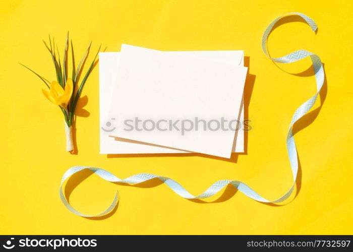 Easter scene with crocus flower over illuminating yellow background, frame with copy space over white paper note. Easter scene with white eggs