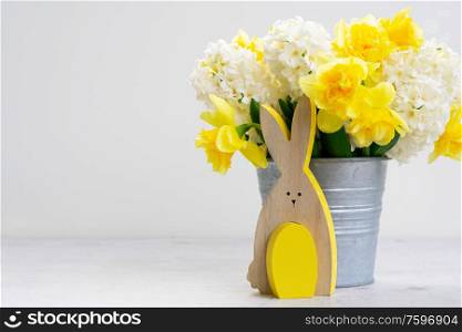 Easter scene with spring flowers bouquet, rabbit and colored egg over white with copy space. Easter scene with colored eggs
