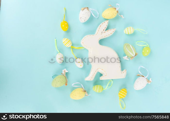 Easter scene with spring flowers, rabbit and colored eggs, flat lay on blue background. Easter scene with colored eggs