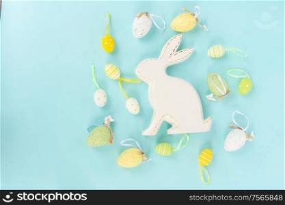 Easter scene with spring flowers, rabbit and colored eggs, flat lay on blue background. Easter scene with colored eggs