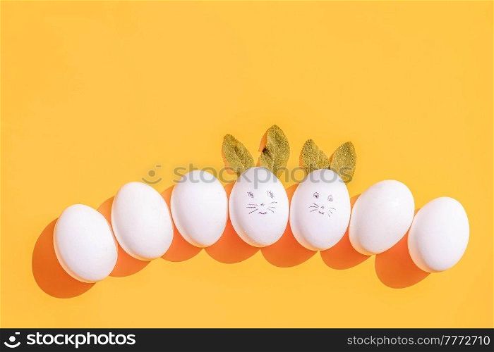 Easter scene with white eggs row with funny faces over illuminating yellow background. Easter scene with white eggs