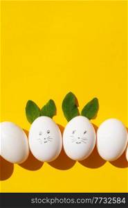 Easter scene with white eggs with funny faces over illuminating yellow background. Easter scene with white eggs