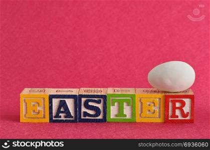 Easter spelled with colorful alphabet blocks displayed with a white easter egg