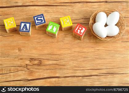 Easter spelled with colorful alphabet blocks displayed with white easter eggs