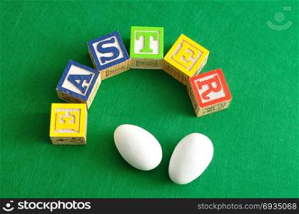 Easter spelled with colorful alphabet blocks displayed with white easter eggs