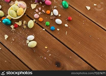 easter, sweets and confectionery concept - chocolate egg and candy drops on wooden table. chocolate egg and candy drops on wooden table