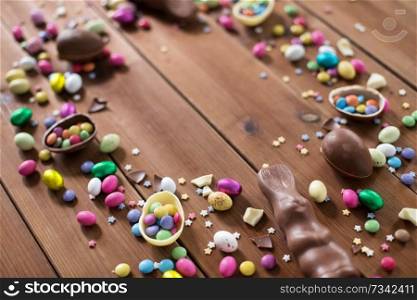 easter, sweets and confectionery concept - chocolate eggs and candy drops on wooden background. chocolate eggs and candy drops on wooden table