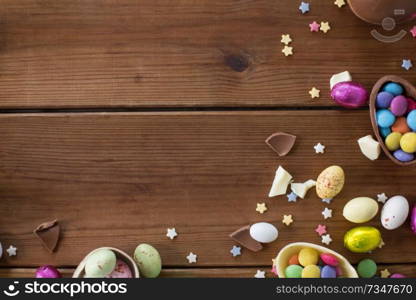 easter, sweets and confectionery concept - chocolate eggs and candy drops on wooden background. chocolate eggs and candy drops on wooden table