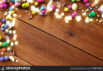 easter, sweets and confectionery concept - chocolate eggs and candy drops on wooden background. chocolate eggs and candy drops on wooden table