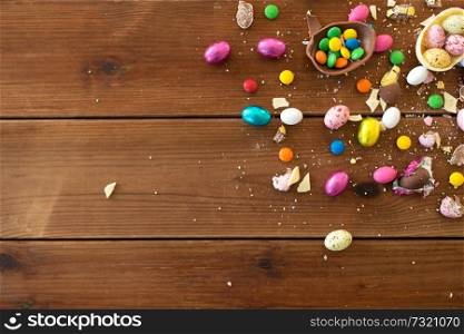 easter, sweets and confectionery concept - chocolate eggs and candy drops on wooden table. chocolate eggs and candy drops on wooden table