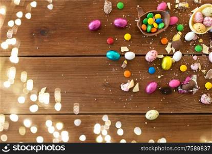 easter, sweets and confectionery concept - chocolate eggs and candy drops on wooden table. chocolate eggs and candy drops on wooden table