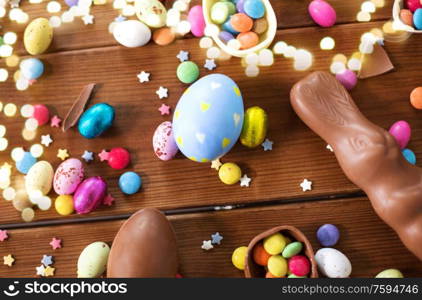 easter, sweets and confectionery concept - chocolate eggs, bunny and candy drops on wooden background. chocolate eggs, easter bunny and candies on wood