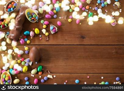 easter, sweets and confectionery concept - chocolate eggs, bunny and candy drops on wooden background. chocolate eggs, easter bunny and candies on wood