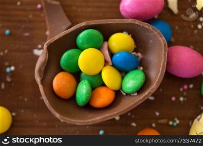 easter, sweets and confectionery concept - close up of chocolate egg and candy drops on wooden table. chocolate egg and candy drops on wooden table