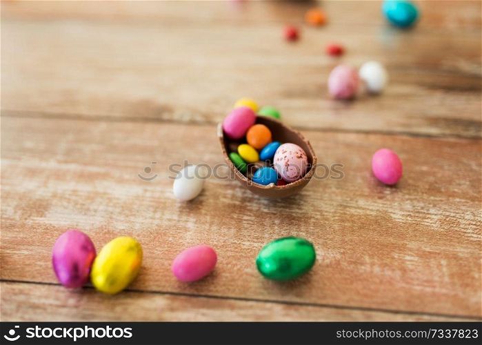 easter, sweets and confectionery concept - close up of chocolate egg and candy drops on wooden table. chocolate egg and candy drops on wooden table