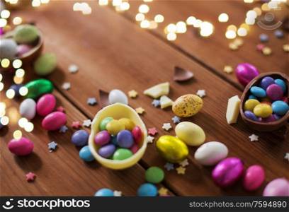 easter, sweets and confectionery concept - close up of chocolate eggs and candy drops on wooden background. chocolate eggs and candy drops on wooden table