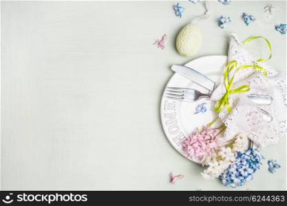 Easter table setting with holiday decoration, hyacinths flowers and egg on light mint wooden background, top view, place for text.