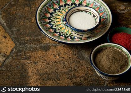 eastern spices in cups on an old worn paving stone. oriental spices on decorative old tiles. oriental spices on an old paving stone