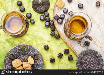 Eastern tea concept.Eastern tea in traditional glass with chocolate candy. Turkish tea in traditional glass