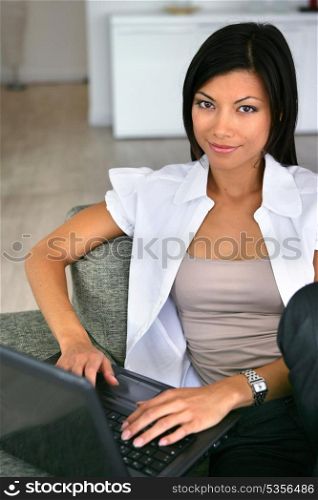 Eastern woman sat on sofa with laptop