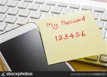 Easy number password handwriting on yellow paper note stick on blank black screen of smartphone with modern white keyboard on background. Internet banking, data privacy and cyber security concepts.